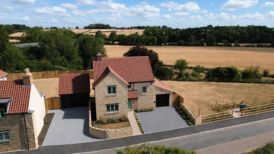 Pepys Lane, Slipton - front elevation of completed stone home with open countryside behind